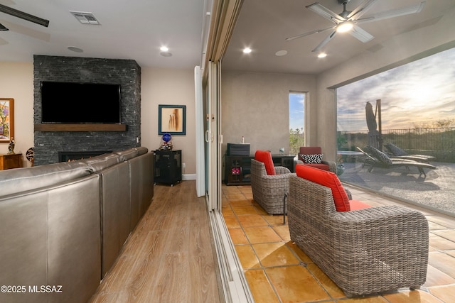 living room featuring light wood finished floors, visible vents, a ceiling fan, a stone fireplace, and recessed lighting