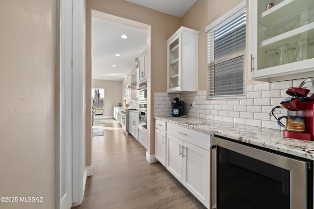 kitchen with glass insert cabinets, beverage cooler, and white cabinets