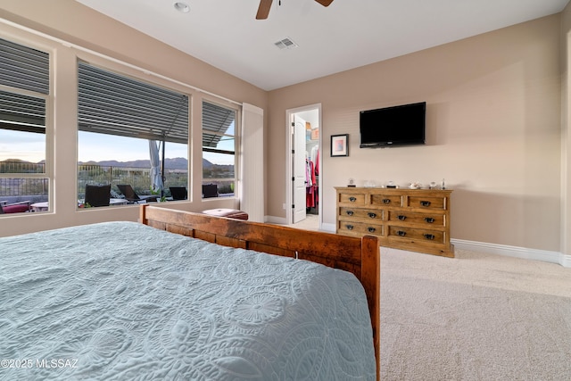 bedroom featuring carpet floors, a walk in closet, visible vents, a ceiling fan, and baseboards