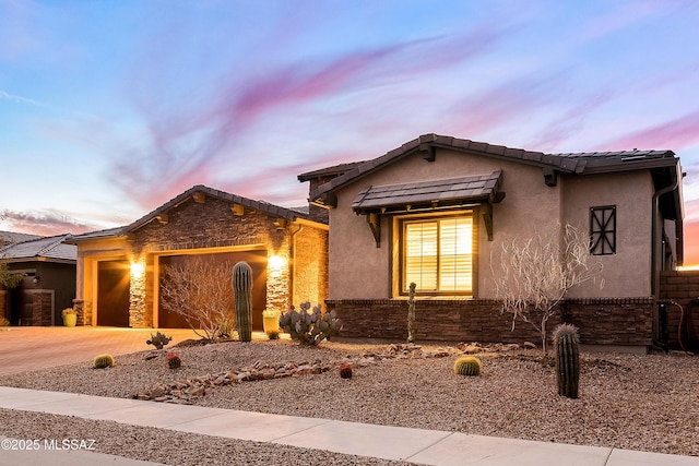 view of front of home with a tile roof, driveway, an attached garage, and stucco siding