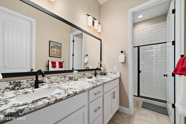 bathroom with double vanity, a stall shower, a sink, and tile patterned floors