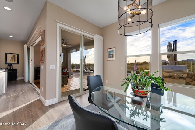 dining area with a wealth of natural light, a notable chandelier, baseboards, and wood finished floors