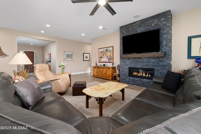 living room featuring light wood finished floors, recessed lighting, and a stone fireplace