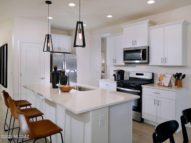 kitchen featuring an island with sink, white cabinetry, stainless steel appliances, and hanging light fixtures