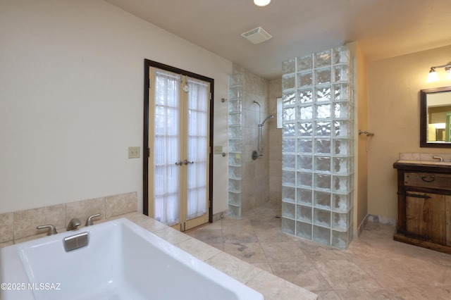 bathroom with a garden tub, visible vents, a walk in shower, and vanity