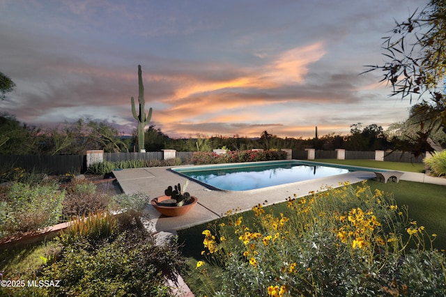 pool at dusk with a fenced in pool, a diving board, a patio, and fence