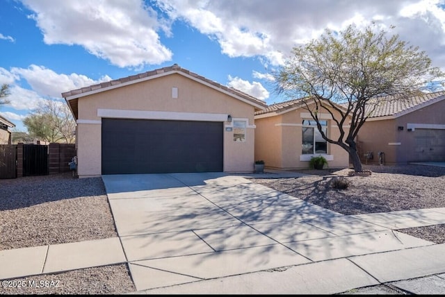 view of front of property featuring an attached garage, fence, concrete driveway, a tiled roof, and stucco siding