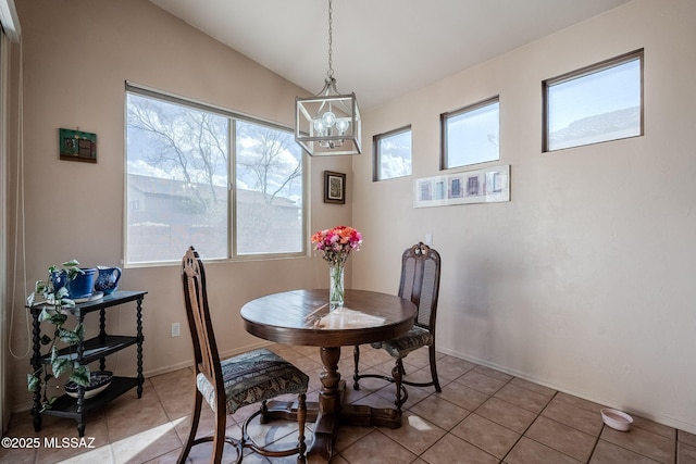 dining space featuring lofted ceiling, light tile patterned floors, baseboards, and a notable chandelier