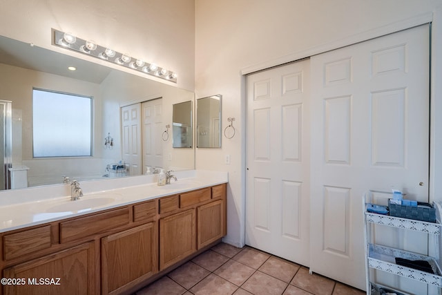 bathroom with double vanity, tile patterned flooring, a sink, and a bath