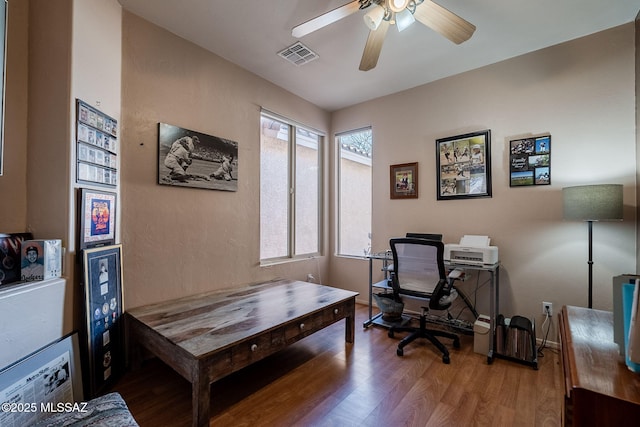 home office with ceiling fan, plenty of natural light, wood finished floors, and visible vents