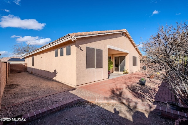 rear view of house featuring a tile roof, a patio area, a fenced backyard, and stucco siding