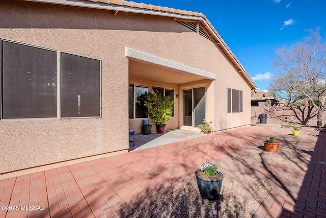 back of property featuring a patio area, a tiled roof, fence, and stucco siding