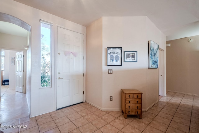foyer featuring arched walkways and light tile patterned flooring