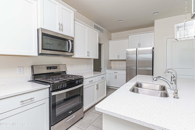 kitchen with appliances with stainless steel finishes, light tile patterned flooring, sink, and white cabinetry