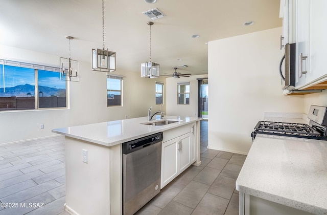 kitchen featuring hanging light fixtures, an island with sink, stainless steel appliances, white cabinets, and sink