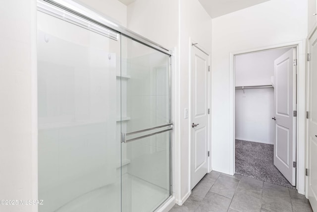 bathroom with a shower with door and tile patterned flooring