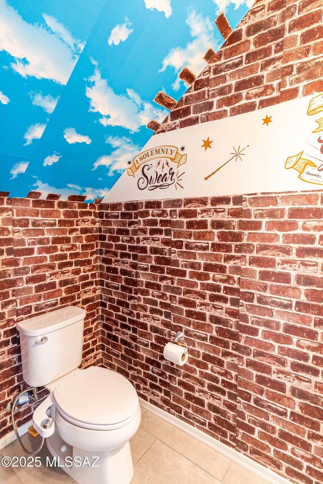 bathroom with tile patterned floors, brick wall, and toilet