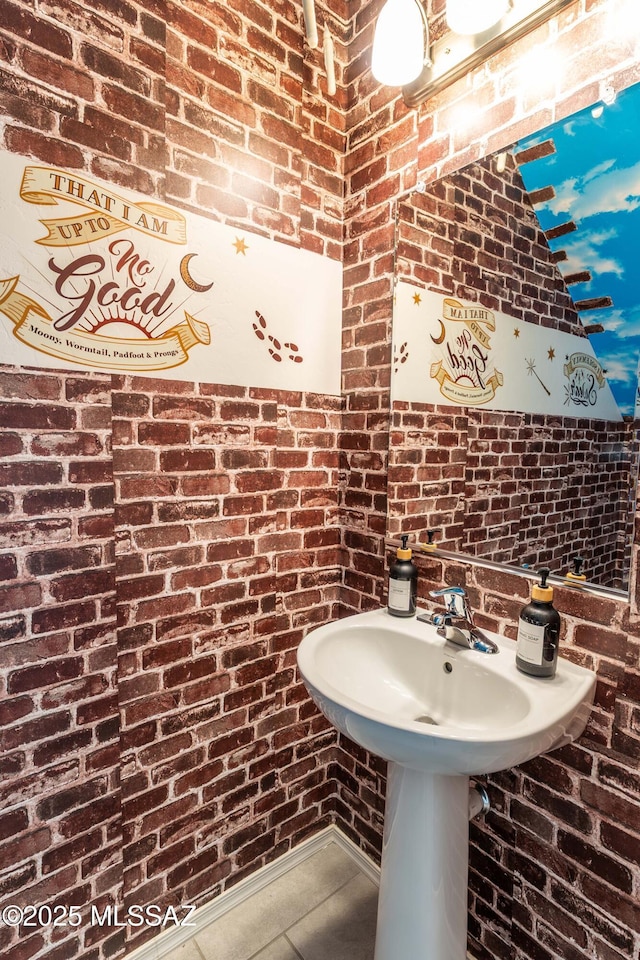 bathroom featuring brick wall and tile patterned flooring