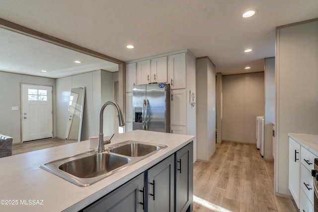 kitchen with stainless steel fridge, light hardwood / wood-style floors, sink, washer and dryer, and white cabinets