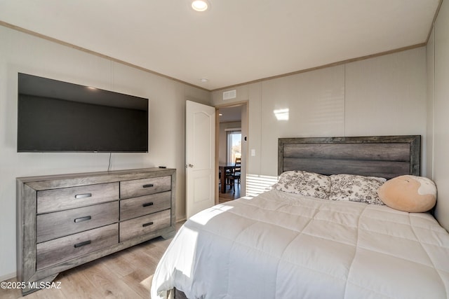 bedroom with ornamental molding and light hardwood / wood-style flooring