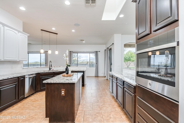 kitchen with a barn door, a sink, a kitchen island, visible vents, and appliances with stainless steel finishes