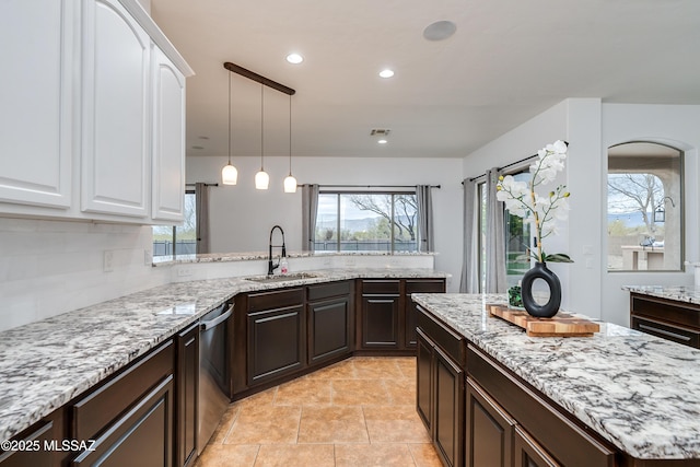 kitchen featuring dark brown cabinetry, white cabinets, a sink, and dishwasher