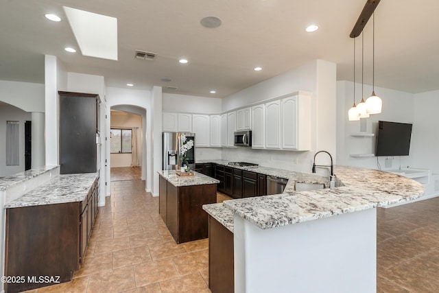 kitchen with visible vents, white cabinets, a peninsula, stainless steel appliances, and a sink