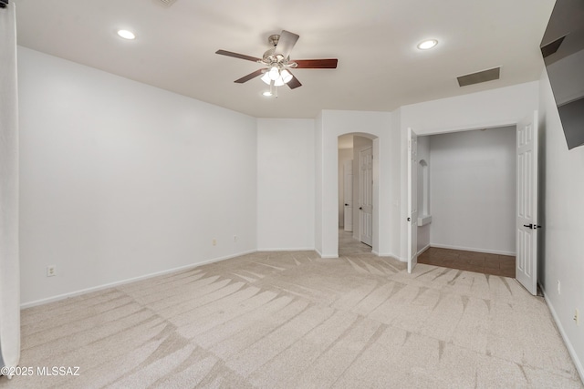 empty room featuring visible vents, arched walkways, baseboards, light colored carpet, and recessed lighting