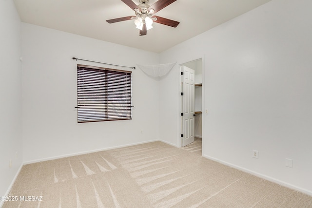 empty room featuring light carpet, a ceiling fan, and baseboards