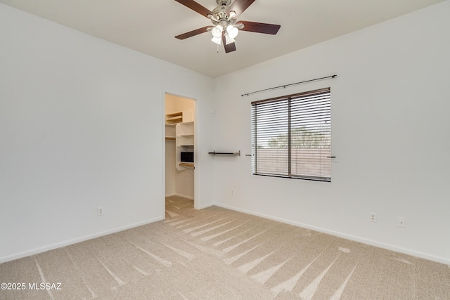 carpeted empty room featuring ceiling fan and baseboards