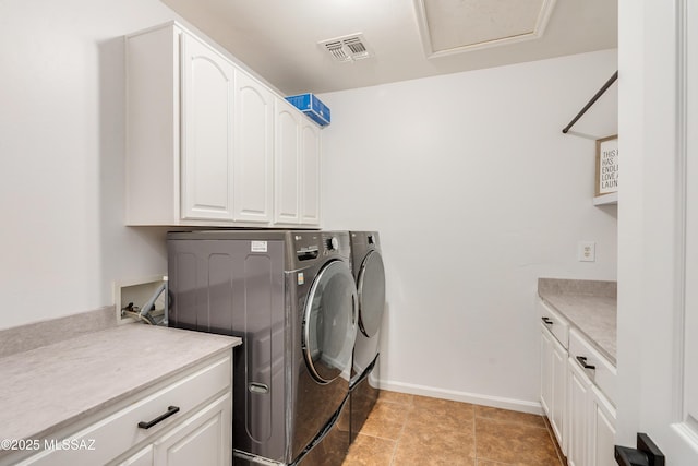 laundry area with visible vents, separate washer and dryer, cabinet space, and baseboards