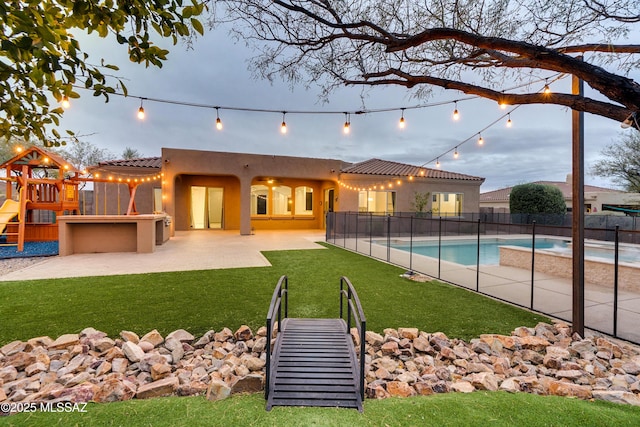 pool at dusk featuring a fenced in pool, a playground, a patio, a lawn, and fence