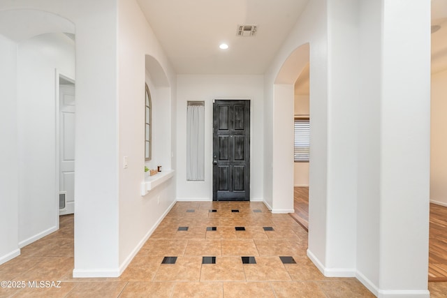 entrance foyer with arched walkways, light tile patterned floors, recessed lighting, visible vents, and baseboards