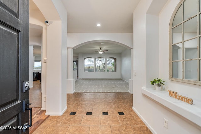 foyer entrance featuring arched walkways, light tile patterned flooring, recessed lighting, a ceiling fan, and baseboards