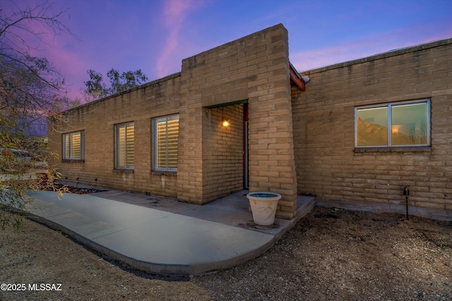 back of house at dusk with brick siding and a patio