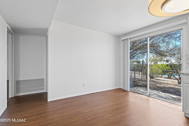 spare room featuring visible vents, baseboards, and wood finished floors