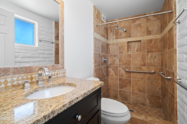 bathroom with tiled shower, vanity, and toilet