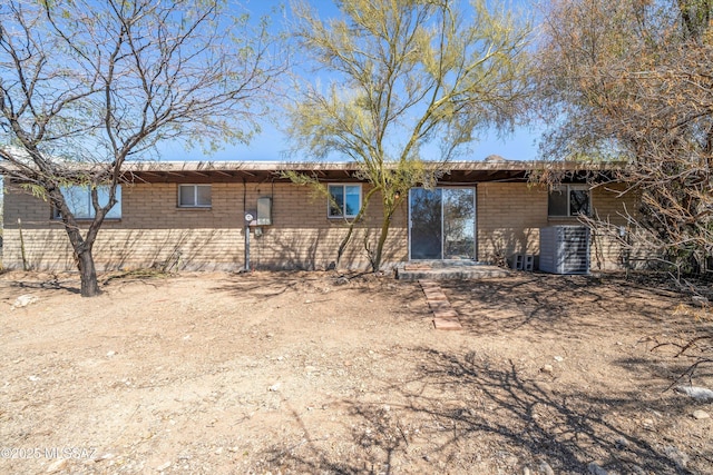 rear view of house with cooling unit and brick siding