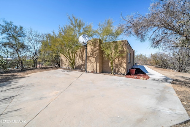 view of side of home featuring driveway and fence