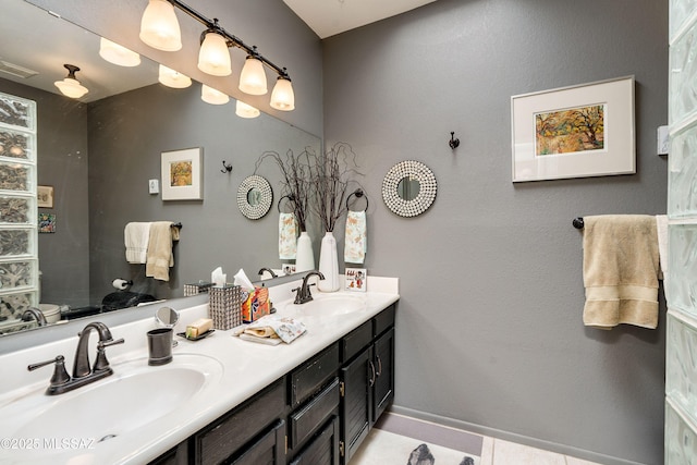 full bathroom with double vanity, a sink, visible vents, and baseboards