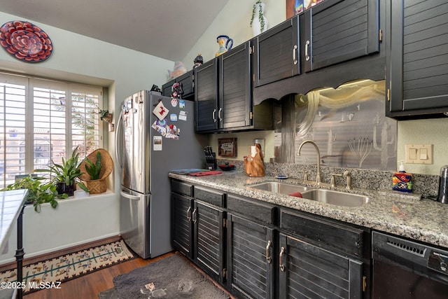 kitchen featuring wood finished floors, freestanding refrigerator, a sink, light stone countertops, and dishwasher