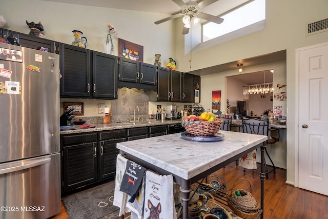 kitchen featuring visible vents, dark cabinetry, dark wood finished floors, and freestanding refrigerator