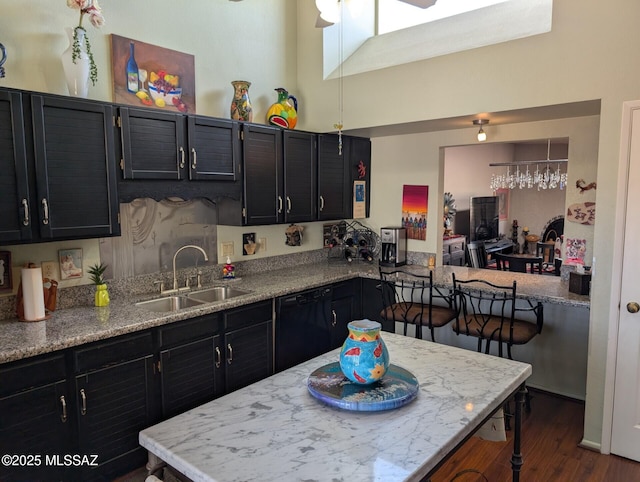 kitchen with dark cabinets, dark wood finished floors, dishwasher, and a sink