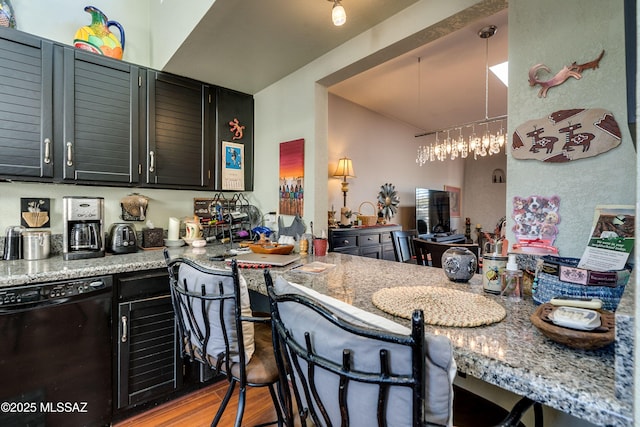 kitchen featuring light wood finished floors, dark cabinets, a breakfast bar area, and dishwasher