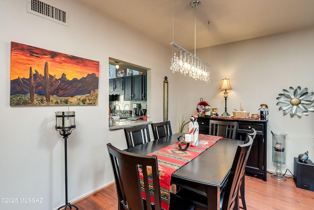 dining room featuring a chandelier, visible vents, baseboards, and wood finished floors