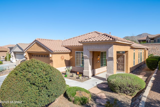 mediterranean / spanish-style home with a garage, a tiled roof, and stucco siding