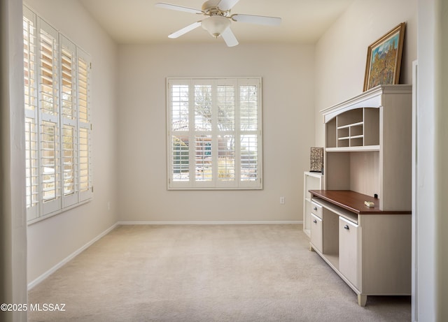 unfurnished office featuring ceiling fan, a wealth of natural light, and light colored carpet