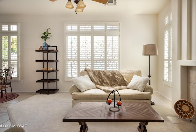 living area featuring light tile patterned floors, baseboards, visible vents, and a ceiling fan