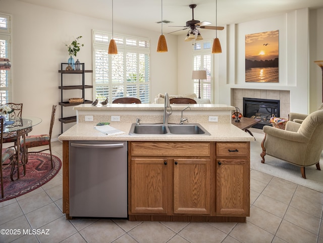 kitchen featuring a tile fireplace, a sink, open floor plan, light countertops, and dishwasher