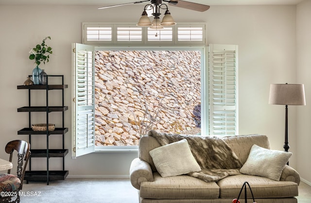 living area with a ceiling fan, carpet, and baseboards